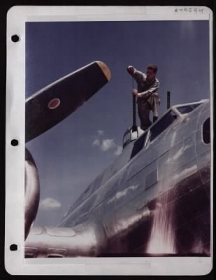 ␀ > Cpl. James E. Dunbar, Mechanic, Runs A Patch Thru Top Turret Guns Of A Boeing B-17 In England.