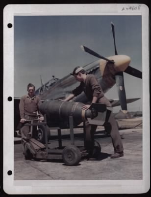 ␀ > Cpl. Leroy Turner Of Altoona, Pa. (Left) And Sgt. Henry A. Bucko Of Hammond, Ind., Wheel Out A 500 Lb. Bomb To Be Loaded On A North American P-51 At A Base In England.