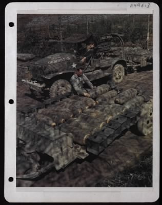 ␀ > Armament Men Load Bombs On A Trailer As A Man Backs A Truck To An Already Loaded Trailer At A Base Somewhere In England. Shadows Are Cast By Camouflage.