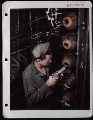 ␀ > Pfc. Lenuel J. Putty Of Morton Gap, Ky., Inserts A Fuse Into A 100 Lb. Bomb Already In The Bomb Bay Of A Consolidated B-24.  England