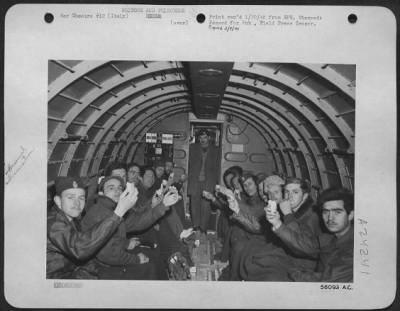 Thumbnail for Consolidated > Wrapped In Blankets, Huddled Together To Keep Warm, The Evacuees Are On Their Way Back To Italy.  They'Re Holding White Bread They Are Eating, The First They Have Had In Many Months.  Officers Of Air Crew Rescue Invariably Carry Along A Few Loaves Of Whit