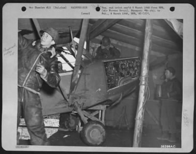 Engines > This is the only hangar for the Liaison Squadron's planes. Just a windbreak for the mechanics, it is made of scrap lumber and a German tent floor. Left to right are: Cpl. Henry Brief, 351 Riverdale Ave., Brooklyn, N.Y.; Sgt. Kirby L. Jensen, Albany