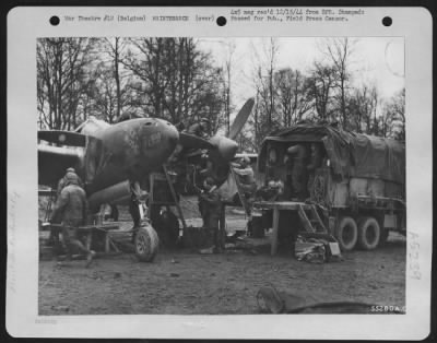 Engines > 9th Air force maintenance men overhaul a Lockheed P-38 Lightning fighter-bomber at an airfield in Belgium. Working around the clock, often in the rain and cold, the ground crewman keep serviceable the planes that are eliminating or neutralizing enemy