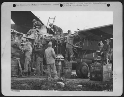 General > 9th Air force maintenance men overhaul a Lockheed P-38 Lightning fighter-bomber at an airfield in Belgium. Working around the clock, often in the rain and cold, the ground crewman keep serviceable the planes that are eliminating or neutralizing enemy
