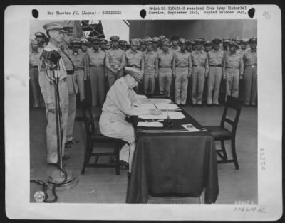 General > General Of The Army Douglas Macarthur Signs As The Supreme Allied Commander During Formal Surrender Ceremonies On The U.S.S. Missouri In Tokyo Bay, August 31, 1945.  Behind Gen. Macarthur Are Lt. Gen. Jonathan Wainwright (Left) Who Surrendered To The Japa