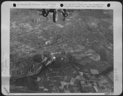 Loubais[Sic] > Black and white smoke rises from direct hits (center) on the railroad marshalling yards at Loubais, Belgium, as a Douglas A-20 Havoc light bomber of the 9th AF, roars over the target.