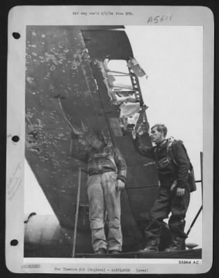 Battle Damage > The flak torn wing of the Consolidated B-24 Liberator "Glass House" is inspected by the pilot (fight) 1st Lt. Louis Novotny, Wilberton, Okla., and the co-pilot 2nd Lt. Robert A. Olson, 1008 Caledonia , St., Butte, Mont., after their return from a