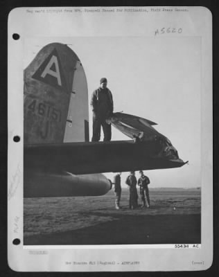 Thumbnail for Battle Damage > Two Flying ofrtresses collided in mid-air over England recently but due to excellent piloting, both were able to land safely at their home base. This photo shows damaged rudder and verticle fin being inspected by part of the ofrtunate crew. Tail