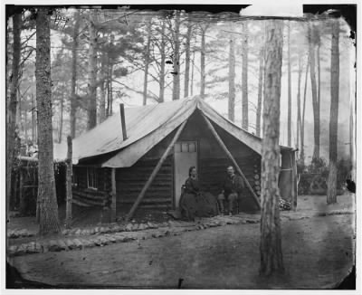 1386 - Brandy Station, Virginia. Col. John R. Coxe, A.C.S., and lady seated before his log-cabin winter quarters at Army of the Potomac headquarters
