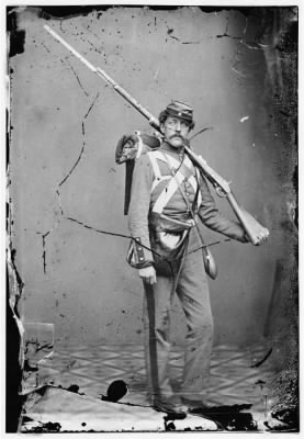 2955 - Unknown location. Unidentified Union volunteer with shouldered rifle and bayonet in photographer's studio