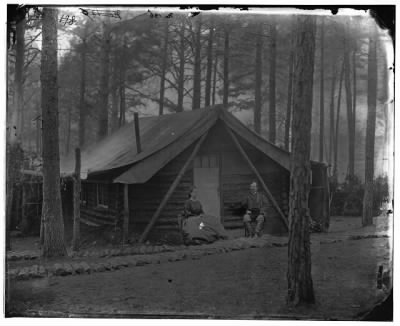 677 - Brandy Station, Va. Col. John R. Coxe, A.C.S., and lady seated before his log-cabin winter quarters at Army of the Potomac headquarters