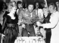 Liberace, Tom Jones, Liberace uses his famed candelabra to light candles on a birthday cake for singer Tom Jones,left to right- Joan Rivers, Joey Heatherton,Sonny Bono, Dionne Warwick, Debby Reynolds.jpg