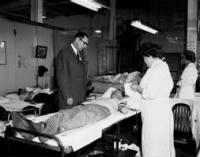 Omer Voss and a Female Nurse Look on as an Employee Donates Blood.jpeg