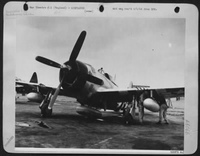 Republic > Ground crewman shown preparing this 8th Air force Republic P-47 Thunderbolt for a long-range bomber escort mission by affixing the auxiliary fuel tanks for additional range. Note tank carried under belly where bomb is otherwise placed.-ENGLAND