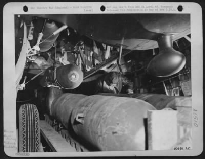 General > Bomb is all set to be swung into position on bomb rack. 500 lb HE bomb is resting on cables of a Portable hoist which lifts the bomb from the bomb cart into position in the bomb-bay. Veteran ground crewmen are seen in the final operations.