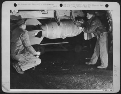 Thumbnail for General > Last touches on a 100 lb demotlition bomb shackled to an external rack underneath a bomber's wing are adminstered by armorers who are inserting big egg's fuse (left) and checking balancing clamps (right).