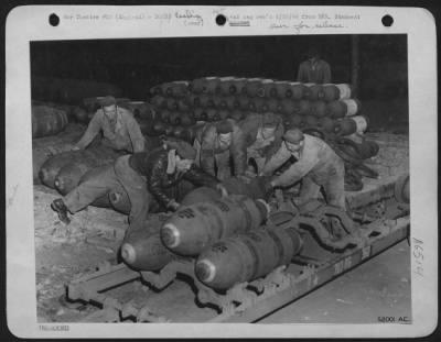 General > Early in the evening preceding the opening assault, armoring crews begin their work of loading great armadas of American heavy bombers. Bombs must be hauled out of their racks in bomb dumps and bomb dispersal areas, placed on racks and pulled