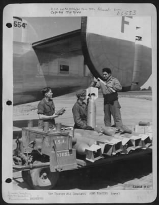 General > Loading bombs in Liberators prior to an operational flight is the job of three ordnance men, member of a group commanded by Col. Luther J. Fairbanks of Burt, Iowa. Left to right: Pfc Jean F. Pentz, 1307 Seventeenth Street, Anacortes, Washington; Cpl.