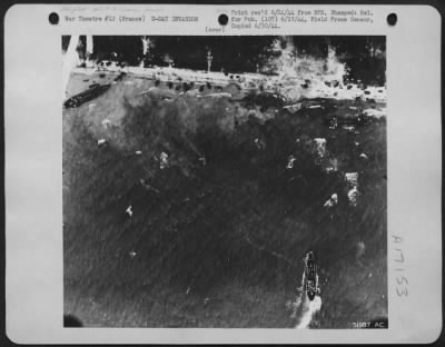 General > Avoiding the great craters left by bombs of the 8th AAF, landing craft nose into the shore somewhere along the beach-head on the coast of Nazi held France.Army vehicles dotting the shore shown in this Eighth Air force Reconnaissance photo.