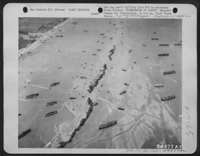 General > American Liberty shiops were deliberately scuttled off the beaches to provide makeshift breakwaters during the early days of the invasion somewhere in France. This scene shows 13 Liberty ships ofrmed into a protecting screen for the vessels