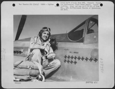 Consolidated > Maj. Sam J. Brown, Tulsa, Okla., Commanding Officer of a North American P-51 Mustang fighter squadron of the Mediterranean Allied Air Forces in Italy, is shown here pointing to the 13 swastikas on his plane which represent the destruction of 13 Nazi