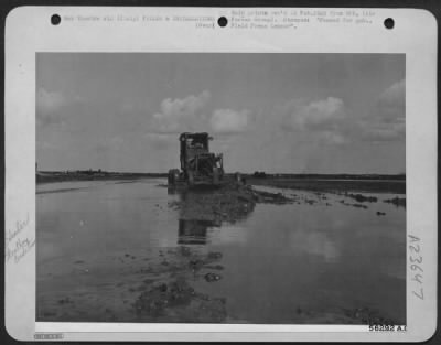 Consolidated > Even while runways are still underwater, aviation engineers carry on the job of maintaining airfields to keep 'em flying, bombing and fighting. Here a motor patrol grader slogs through mud and water to level the surface. ITALY
