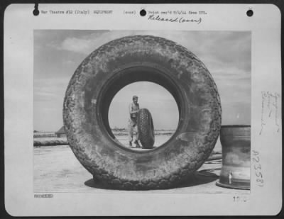 Consolidated > Sgt. R.G. Stallmeyer, 321 Trevor St., Covington, Ky, A Ground Crewman At A Boeing B-17 "Flying Fortress" Base In The 15Th Af, Italy, Is Framed By A 150 Pound Airplane Tires As He Rolls Another One.  [The Pictured Shows Two Good Reasons For Rationing Tires