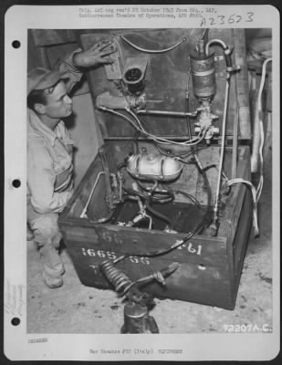 Consolidated > M/Sgt. Woodrow J. Wingo Of Lexington, Sc, A Member Of Rickenbacker'S 'Hat In The Ring' Squadron Of The 15Th Af Based In Italy, Poses With A Test Chest He Constructed Of Salvaged Plane Parts, A Heating Unit For Controls, Pressure Pump, Circulating Hand Pum