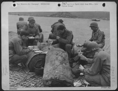 Consolidated > Aviation Engineers Of The Ix Engineer Command, Building An Airstrip In Germany For 9Th Af Fighter Bombers, Have Their Noonday Chow In The Open.  Food Is Served On The Line With Rolls Of Prefabricated Bituminous Surfacing (Pbs) As "Tables."