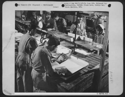 Consolidated > In this section of one laboratory-only one of the many used by aerial reconnaissance section-several teams of men are at work making some of the prints that result from one photo-reconnaissance mission. The teamwork here pays off in increased