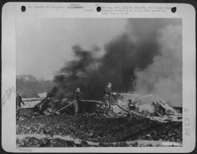 Consolidated > Fire fighters, on the job 24 hours a day at this Eighth Air force Boeing B-17 Flying ofrtress station, are pictured here extinguishing the flames from a burning ofrtress which crashed near this airfield. The stricken ofrtress exploded shortly after