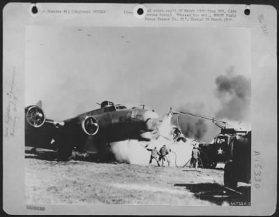 Consolidated > ENGLAND, March 21, 1945-Fire fighters working to extinguish fire fast consuming the left wing of a Boeing B-17 Flying ofrtress. Only one member of the plane's crew was slightly injured.