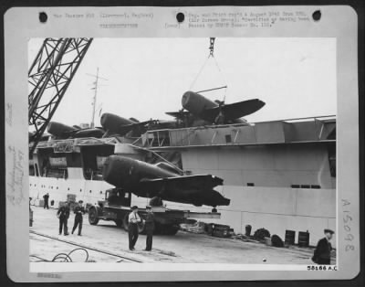 Consolidated > Re-Deployment -- Fighter Planes - At The Liverpool Docks, Huge 60 Ton Cranes Gently Lift A 6 3/4 Ton Republic P-47 Thunderbolt To The Flight Deck Of A Grain Ship Converted Into A Pocket Aircraft Carrier.  These Are The Ships Which Doubled As Baby Flat-Top
