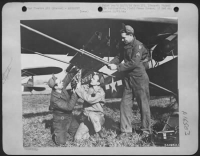 Thumbnail for General > The bazooka gun, heretoofre strictly a ground weapon, converts this Piper Cub Artillery Liaison plane into a rocket-firing craft. Three 9th Air force Service Command armament specialists are pictured installing the bazookas under a wing of the plane