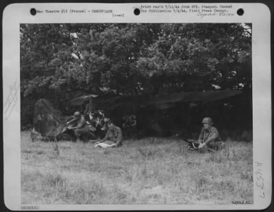 General > With one crew member standing guard with a machine gun the others are busily camouflaging the small plane used near the front lines to spot artillery fire. Left to right are: Cpl. N.A. Atherton, Chicago, radio-man; Pvt. Peter Palermo, Plaquemine, La.