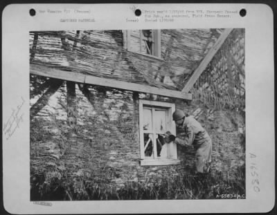 General > Cpl. Marion R. Sams of High Point, N.C., eavesdrops through the paper window of one of the house's constructed by the Nazi for the purpose of camouflaging some small workshops in France.