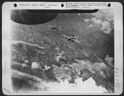 Consolidated > Two North American B-25 airplanes "Mitchell" medium bombers of the Northwest African Air Forces wheel over German gun positions along the Volturno River, north of Naples, Italy. A long line of bombs from other planes in the formation may be seen