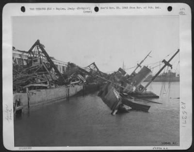 Thumbnail for Consolidated > Dockside facilities at Naples, battered by the bombers of the Northwest African Air Forces, suffered further damage at the hands of the retreating Germans. This picture shows a Italian ship sunk by the German.