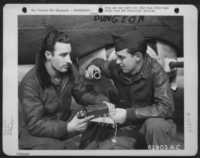 Cameras,Gun > Crew Members Of The 303Rd Bomb Group Check The Machine Gun Camera Which Will Be Installed In The Boeing B-17 "Flying Fortress" In The Background.  England, 13 March 1945.