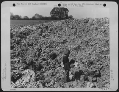 Intruder Damage > A Near Miss Was This Bomb Dropped By An Enemy Night Raider Somewhere In England.  This Crater And One Adjacent To It Made By A Bomb Which Dug Deeply Into The Soft Soil Near A Taxiway At An Airdrome.  The Officer Standing At The Bottom Of The Pit Is Reachi