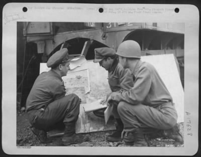 General > The pilot (center) about to go on a Photographic mission is briefed with the aid of a map at a 9th AF base in France. (Left to right) are: 1st Lt. William J. Hohner, Franklin, Ohio; Lt. James M. Poole, Jr., Los Angeles, Calif., (pilot); and Capt.