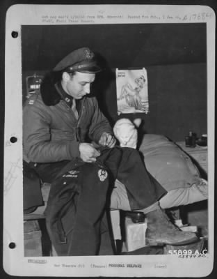 General > Major (then capt) William E. Smith, 485 Central Ave., Hapeville, Ga., said to be the best bombardier in the Ninth AF, repairs clothing ravaged by rats as his recently requisitioned "combat cat," (Joan L. Sullivan) observes. Major Smith, a Martin B-26
