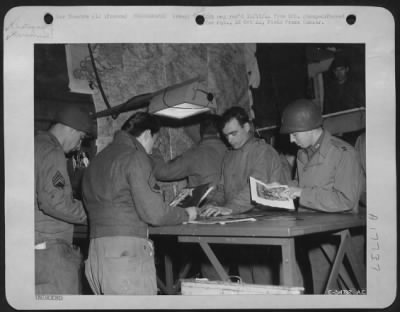 Processing > Looking over some finished prints in a photo lab of a Photo Recon Unit somewhere in France are (left to right) S/Sgt Paul Ftak, Jr., of Chicago, Ill.; S/Sgt John Kachuba of Long Island City, N.Y.; T/Sgt Russel L. Herbruck of Cleveland, Ohio; Cpl
