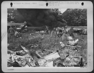 Thumbnail for General > American troops search the burning wreckage of a crashed liberator for equipment. This plane was disabled while on a bombing mission over France and crashed in a field after its crew had bailed out safely.