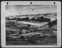 AS SUPPLIES POUR ASHORE for THE INVASION OF FRANCE. Photo made by a U.S. Coast Guard combat photographer from a hillside cut with the trenches of the ousted Nazi. The waters are flocked with shipping as reinforcements and supplies - Page 1