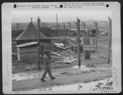 Consolidated > A guard walks his post around the stockade at an 11th Air Force base in Amchitca, Aleutian Islands. 12 October 1943.