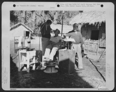 Consolidated > At Hailakandi, India, The Dental Officer Maintained An Outdoor Clinic, Using A Grass Awning For A Sunshade.  Here, He Gives Dental Treatment To One Of The Men Of The 1St Air Commando Force.