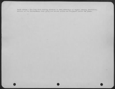 Consolidated > North Africa-Too busy with bombing missions to take advantage of regular messing facilities, members of the Earthquakers bomb group are served coffee and doughnuts beside the plane.