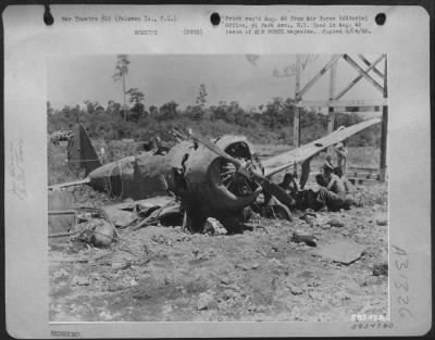 Consolidated > In the shadow of a Jap fighter's wing, construction workers erecting a new control tower stop for a swig of water and a few minutes of rest. Palawan Island, P.I.