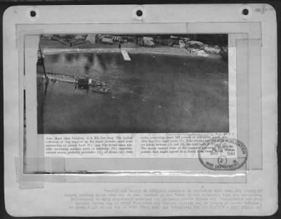 Consolidated > JAN SUPPLY DUMP-A 5,500 ton Jap freighter, 385 feet long, lies on the bottom off a beach at Vunapope, south of Rabaul on New Britain Island. Jap supplies, piled on the beach, include food and ammunition. The evenly spaced trees of the coconut